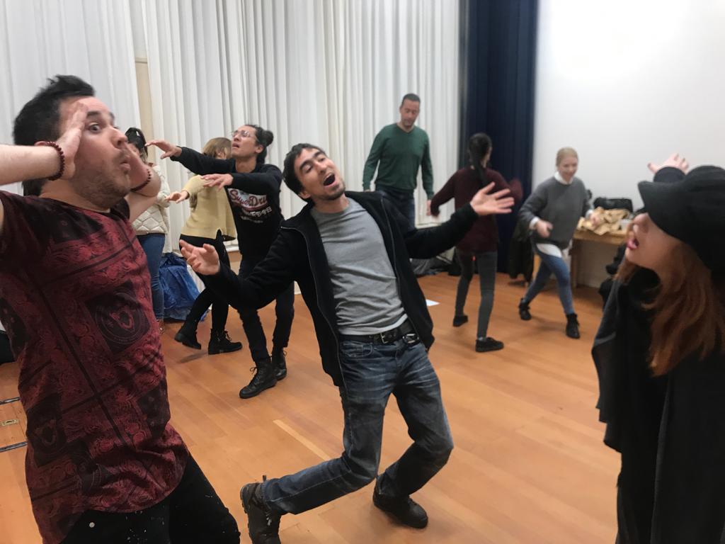 Act Attack's Improv and physical acting class. Two men are singing or they look shocked, while everyone else from the rest of the group does something different